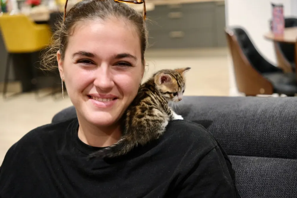 Kelly souriante avec un chaton sur l'épaule
